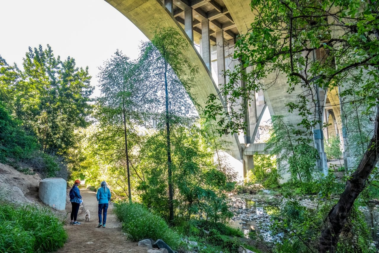 Walkers on the Arroyo Seco Trail in Lower Arroyo Park, with the trail and surrounding landscape in view.