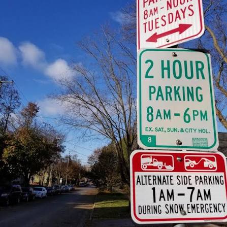 Posted parking restrictions along a tree-lined residential street in Madison Heights, with curbside spaces visible.